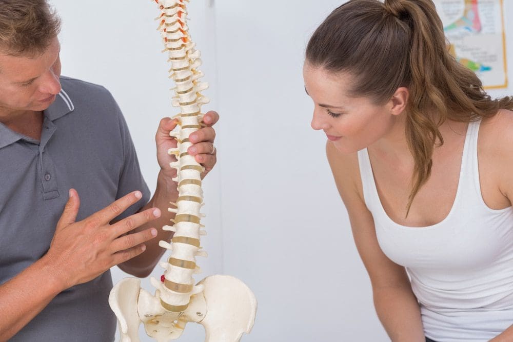 Doctor,Showing,Anatomical,Spine,To,His,Patient,In,Medical,Office