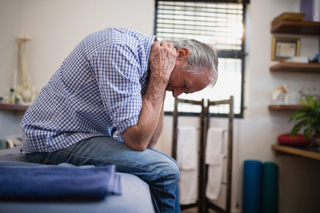 Side view of senior man sitting with neck pain on bed 11860 Vista Del Sol, Ste. 128 Chronic Pain Throughout the United States