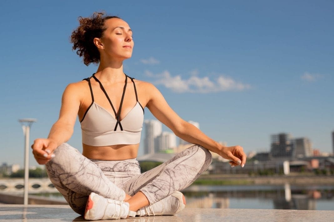 Pretty brunette sportswoman in tanktop and leggins sitting in pose of lotus 11860 Vista Del Sol, Ste. 128 Breathing and Meditation for Back Pain