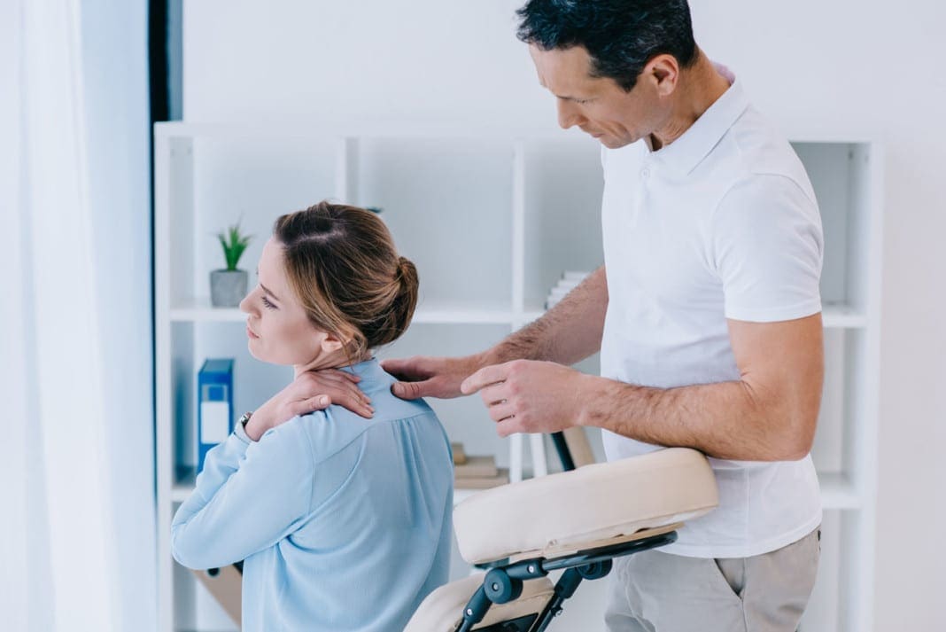 masseur looking at client with neckpain at office 11860 Vista Del Sol, Ste. 128 The Atlas Vertebra Key To Maintaining Head Balance And Alignment