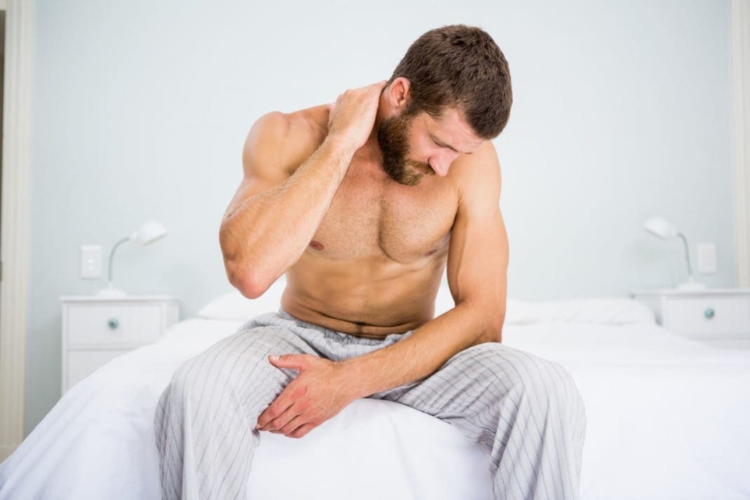 Man suffering from neck ache on bed at bedroom