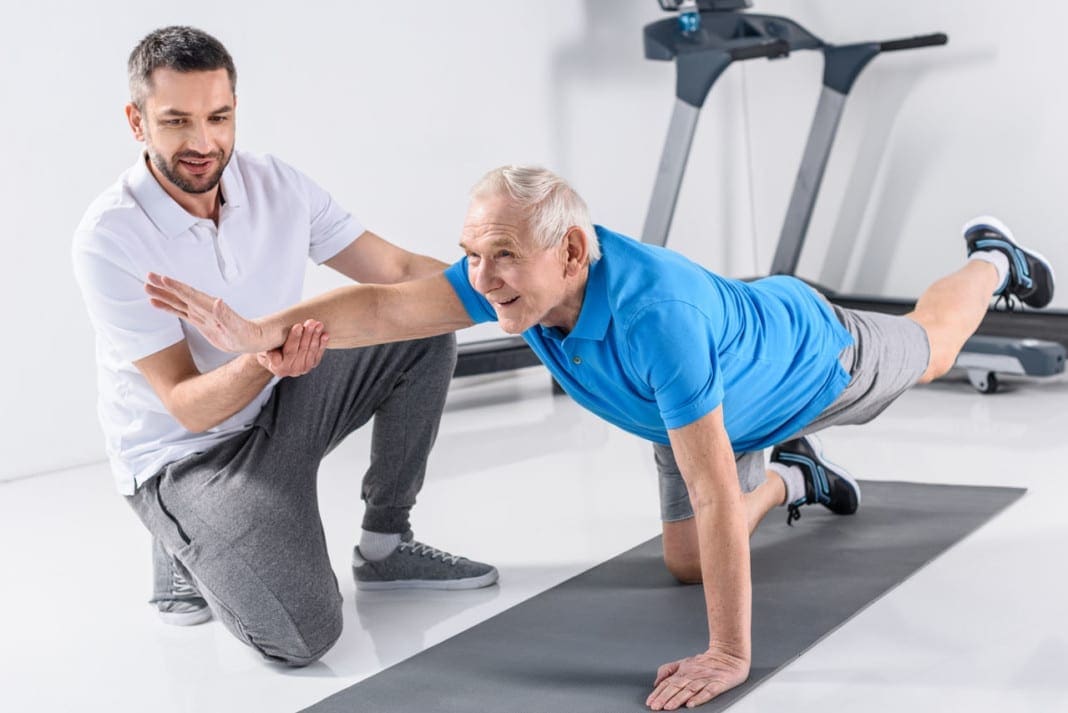 rehabilitation therapist helping smiling senior man exercising o 11860 Vista Del Sol, Ste. 128 Don't Give Up On Physical Therapy For Back Pain