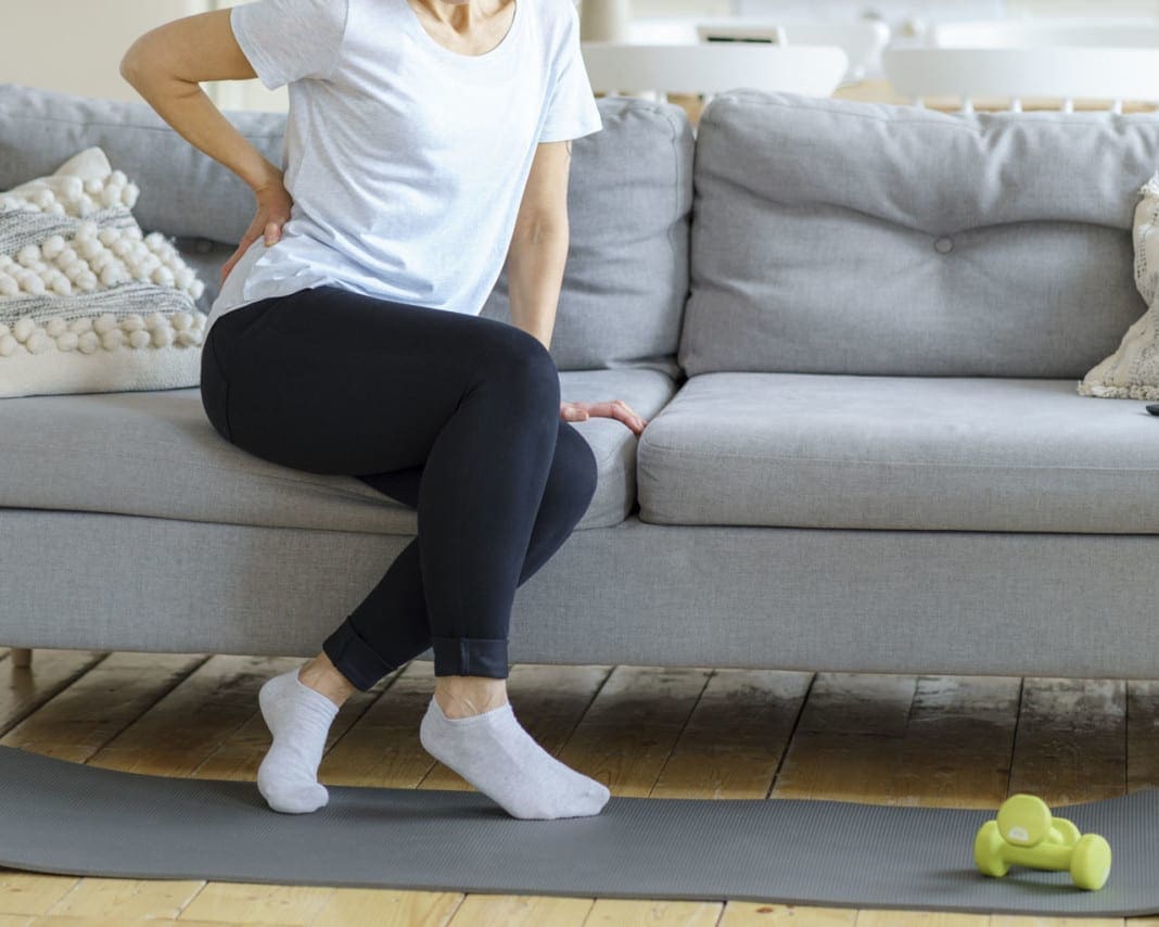 Senior adult woman touching back feeling backache, discomfort low lumbar muscular kidney pain