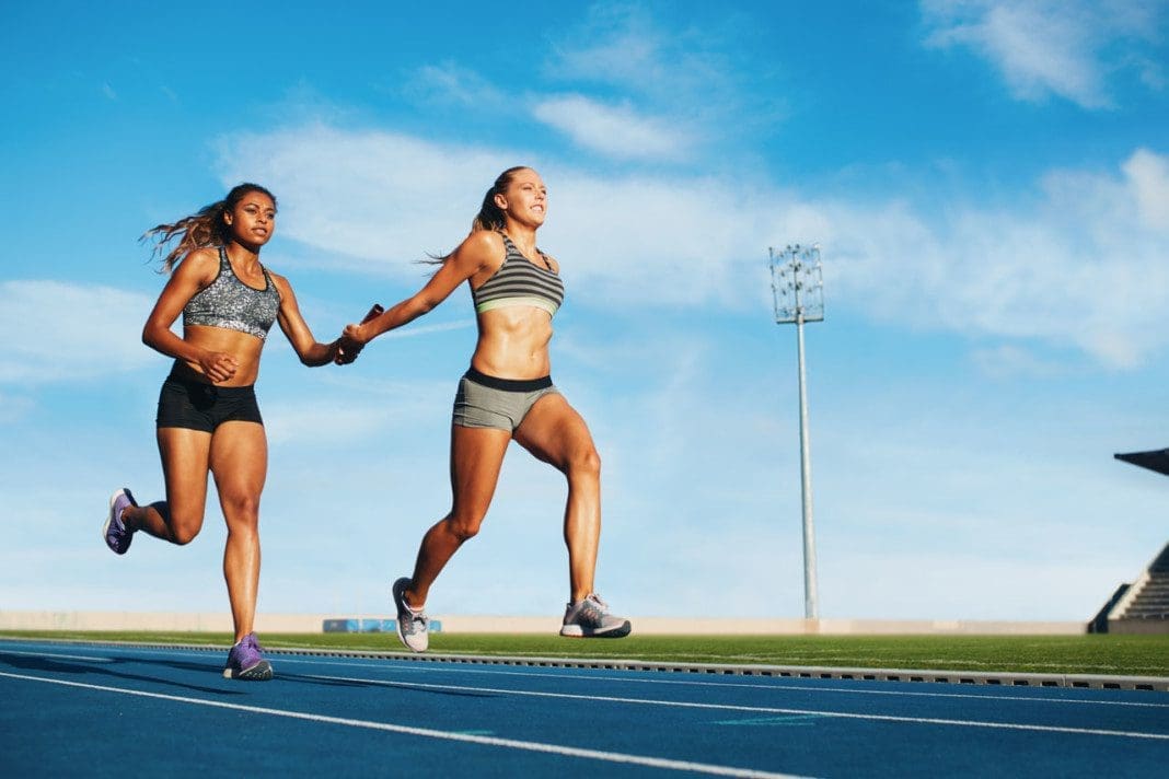 Female relay racing team on racetrack