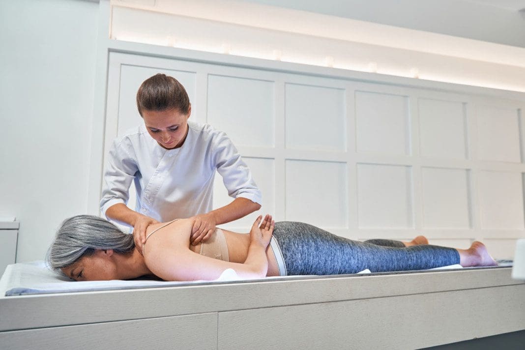 Concentrated brunette woman doing professional recovery massage