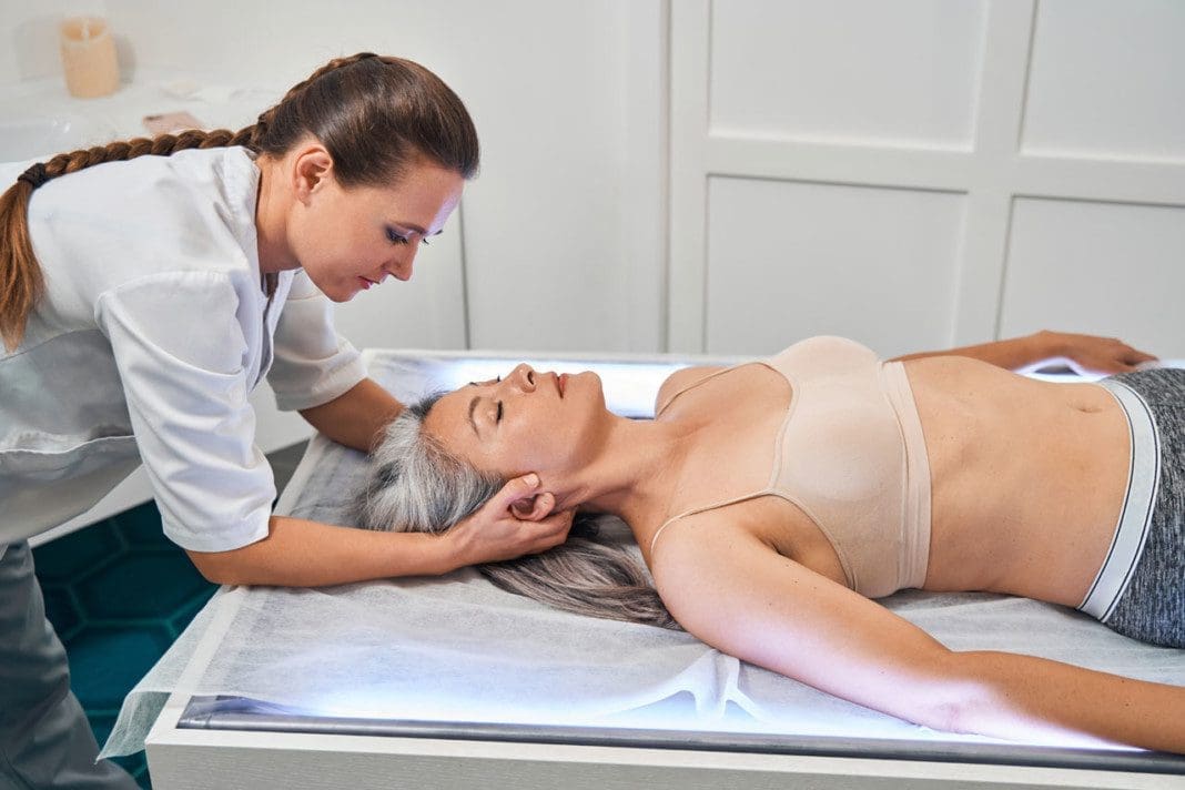 Young professional osteopath checking work of muscles