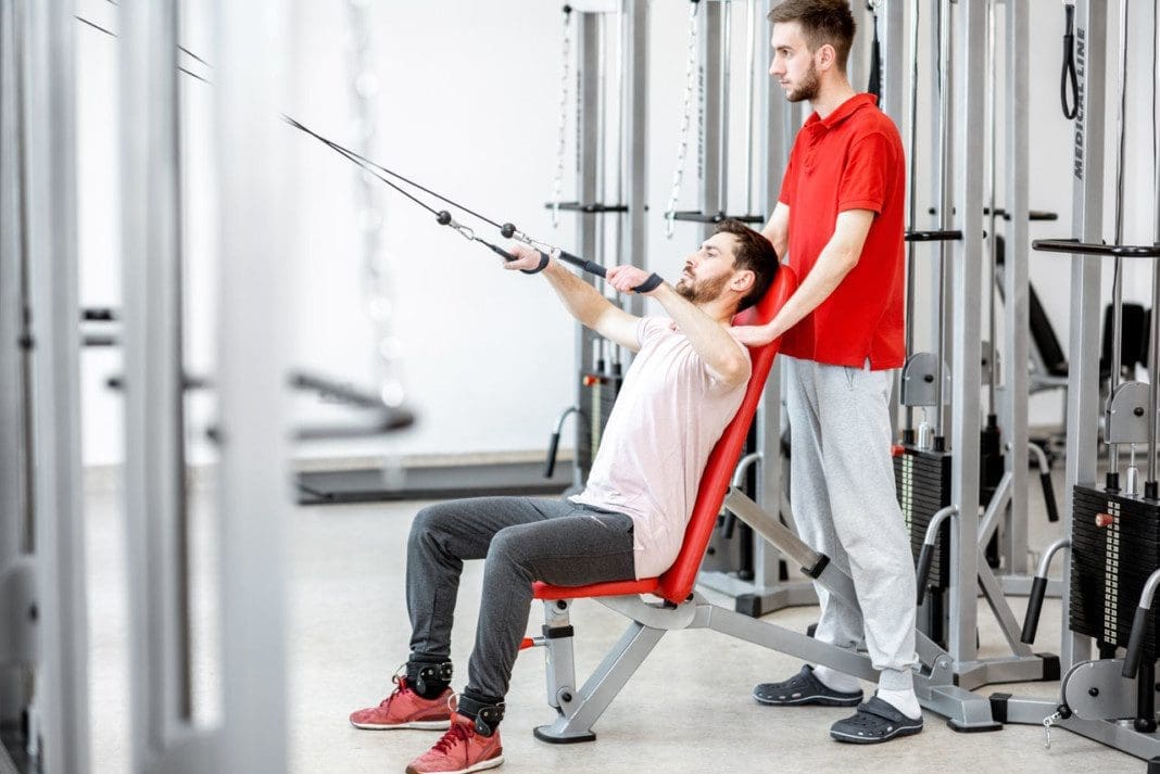 Man exercising with trainer at the rehabilitaion gym