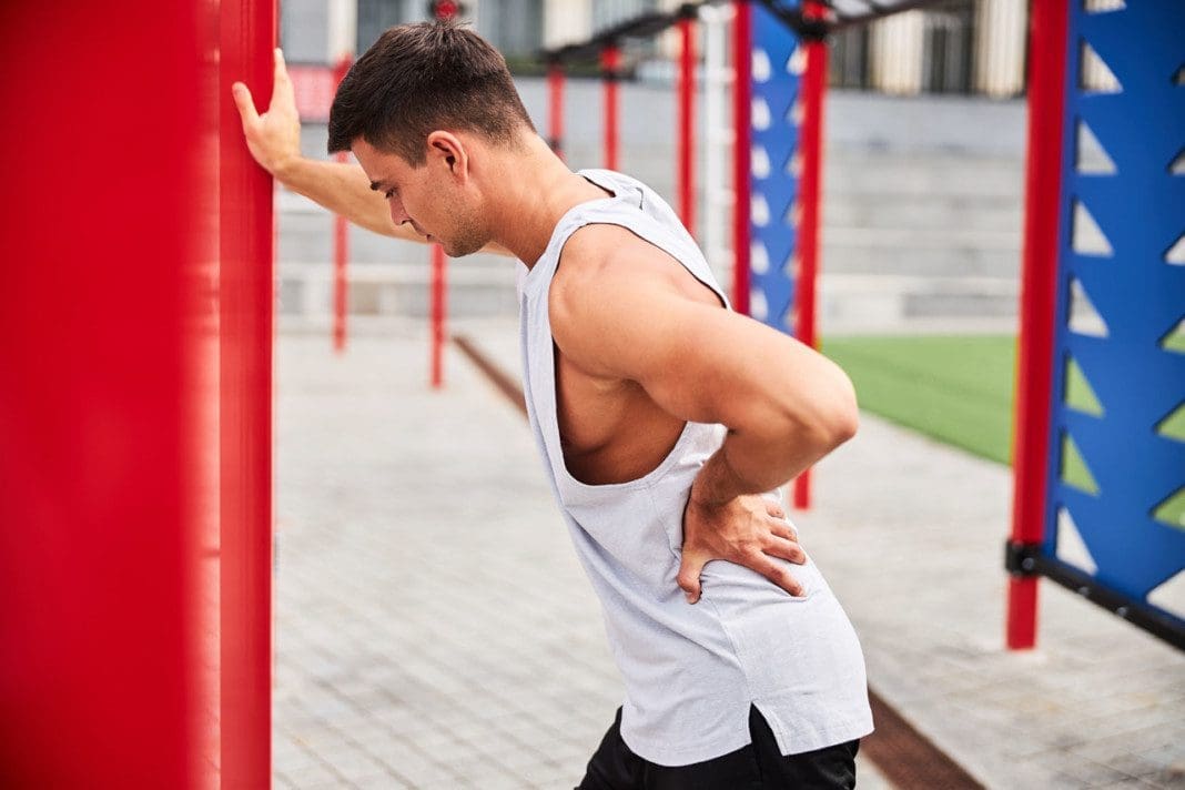 Athletic young man exhausted after training on sports ground