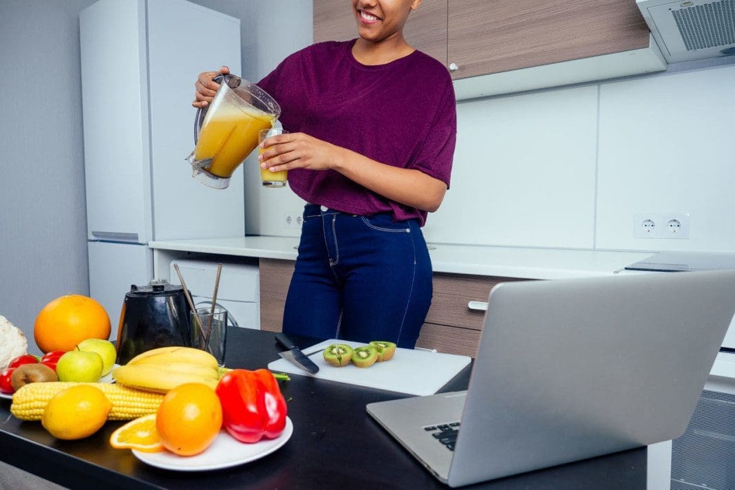 latino woman working at juice bar and cutting fruits, making fresh smoothies from bananas,orange and melon. she useing eco metal reusable tubes and glass