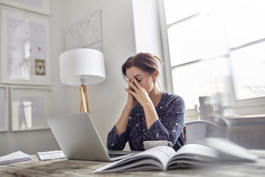 Image: Tired, stressed businesswoman at laptop with head in hands