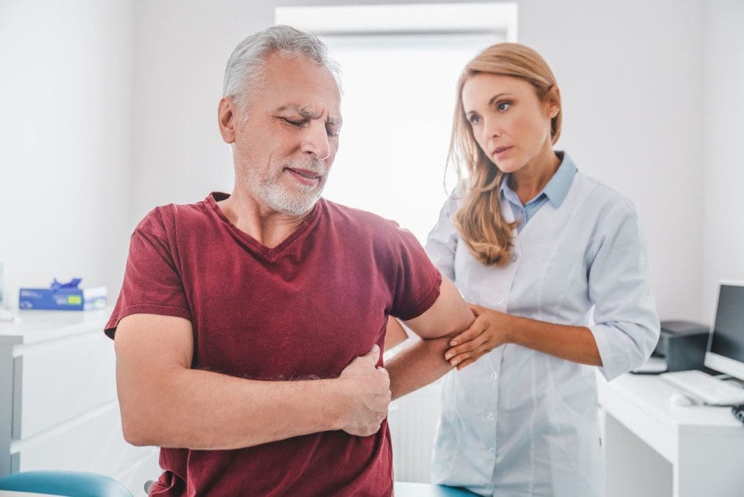 Adult female orthopedist examining patient's back in clinic