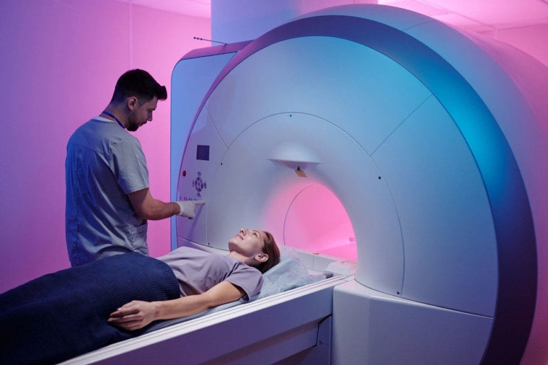 Young doctor pushing button on panel to start mri scan procedure