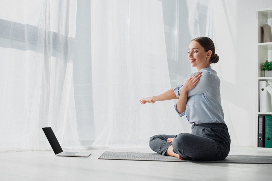 young businesswoman having online classes on laptop and stretchi