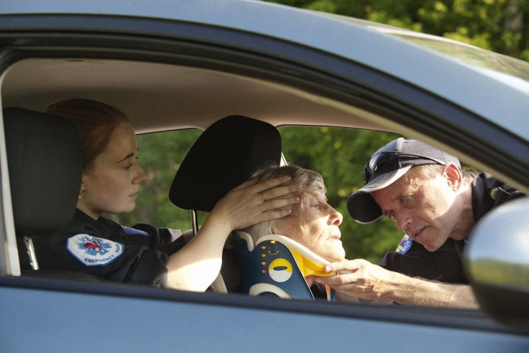 Paramedics Putting Neck Brace On Patient In Car