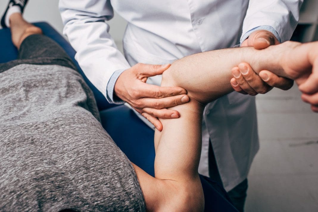 cropped view of chiropractor massaging arm of patient in hospita