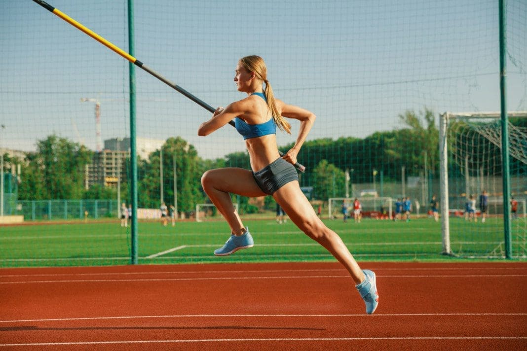 Female high jumper training at the stadium in sunny day