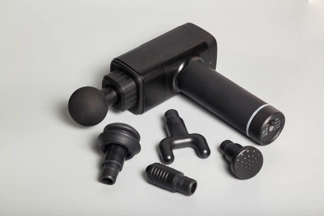 Percussion massager of deep muscle tissues for athletes, relaxes. Close up handheld wireless professional therapeutic shock massage gun