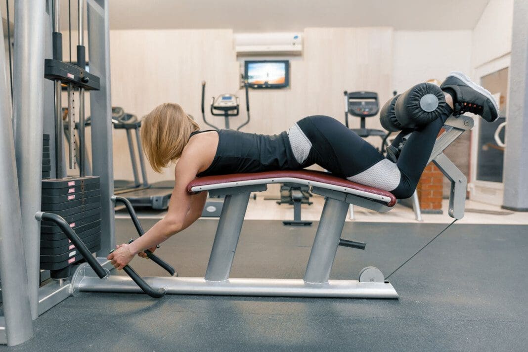 Young athletic woman doing exercises on legs and buttocks in gym. Sport, fitness, bodybuilding, training, healthy lifestyle concept