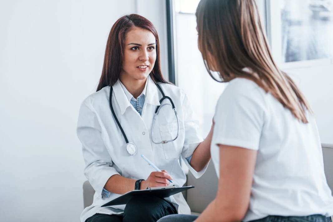 Sitting and talking. Young woman have a visit with female doctor in modern clinic