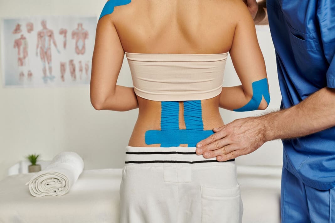 back view of woman on appointment with doctor who putting kinesi