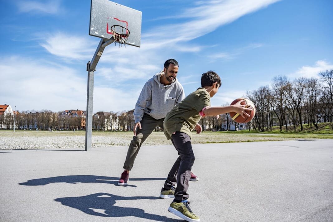 Father and son playing basketball on court outdoors