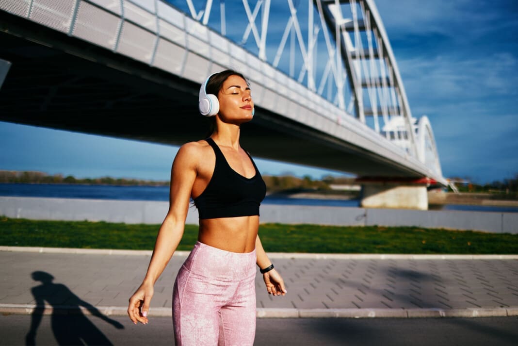 Young fitness woman resting after jogging in the city by the river and bridge