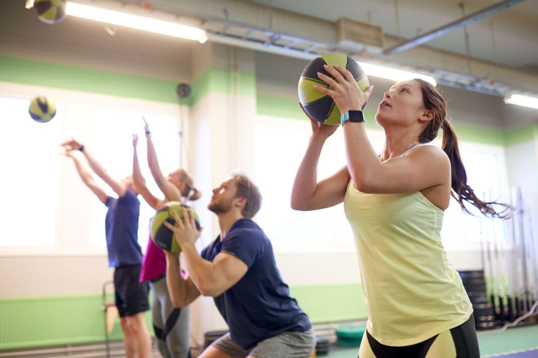 group of people with medicine ball training in gym