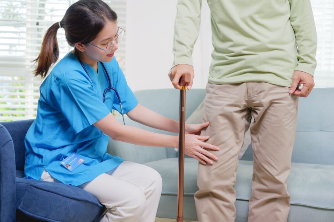 Elderly patient trying to stand and walking with caregiver nurse