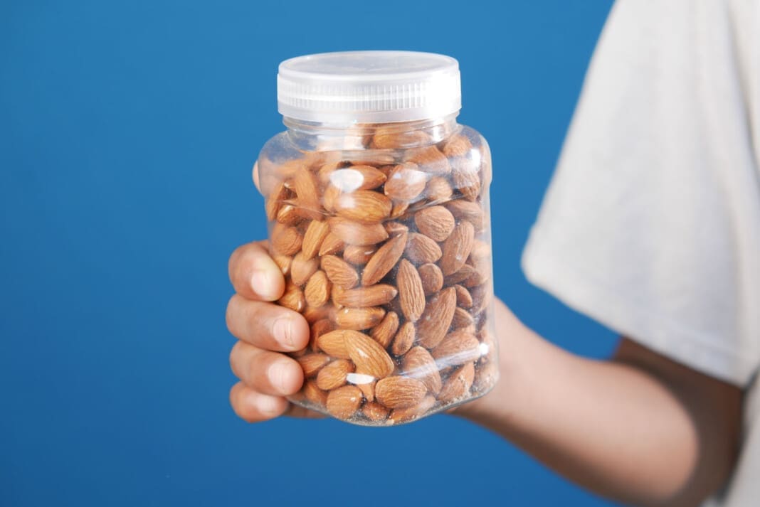 hand hold a jar of a almond nuts with copy space
