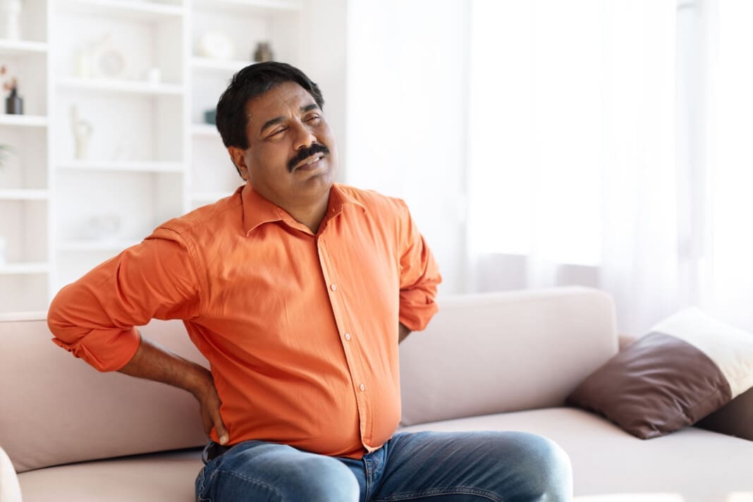 Suffering middle aged indian man feeling lower back pain