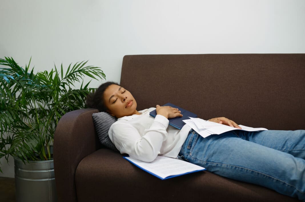 Tired woman worker sleeping on sofa in corporate office