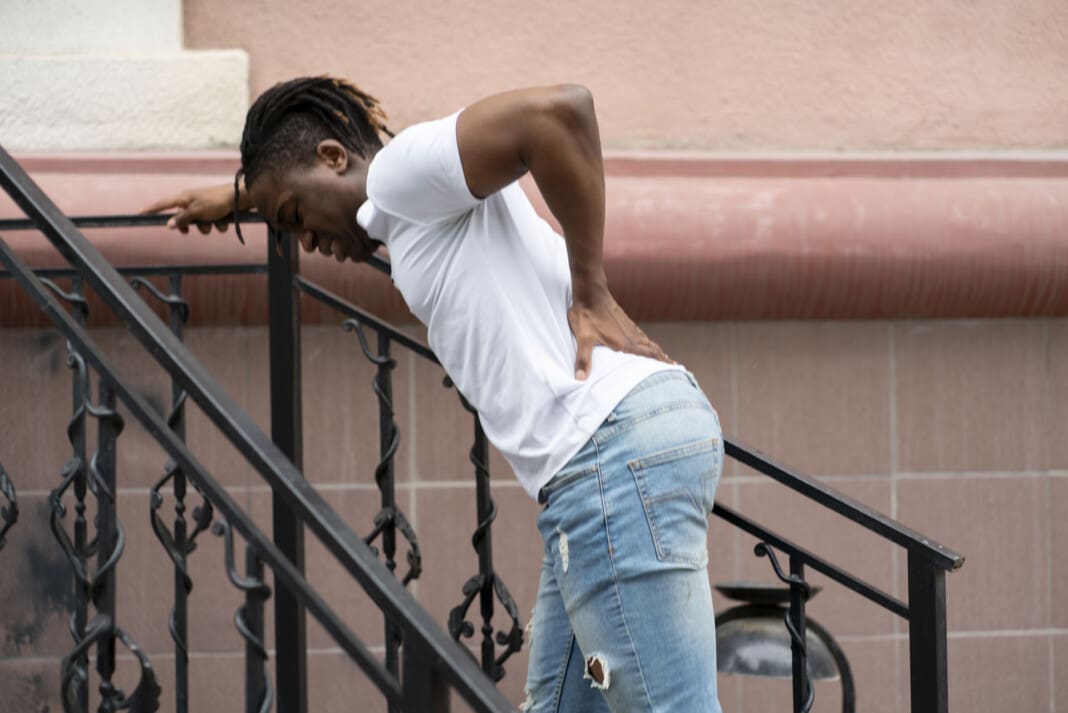feeling sudden awful back pain, a young african american suffering from injury