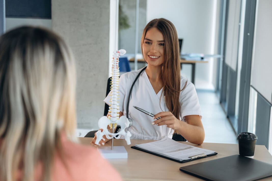Spine problems, showing issue on model. Woman is on the consultation with doctor in clinic