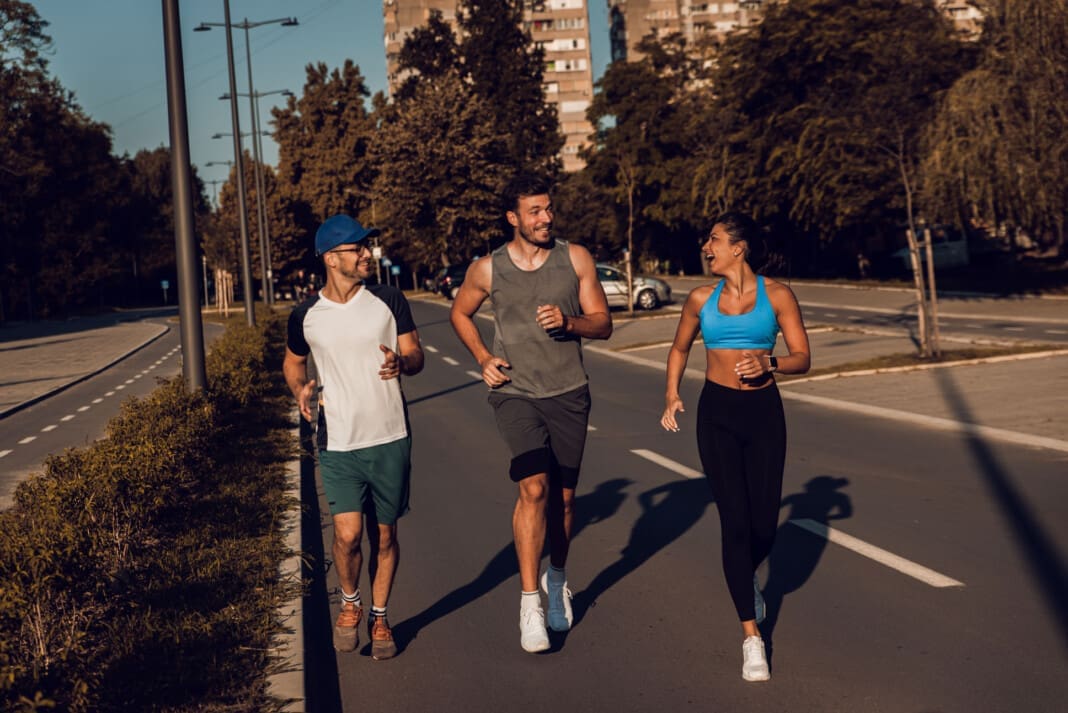 Group of friends running in city street in morning.