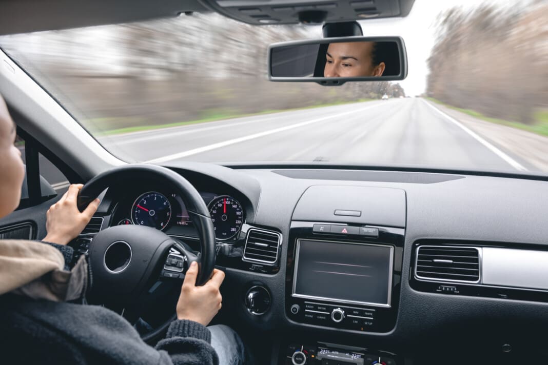 Woman driver's hands on a car steering wheel.
