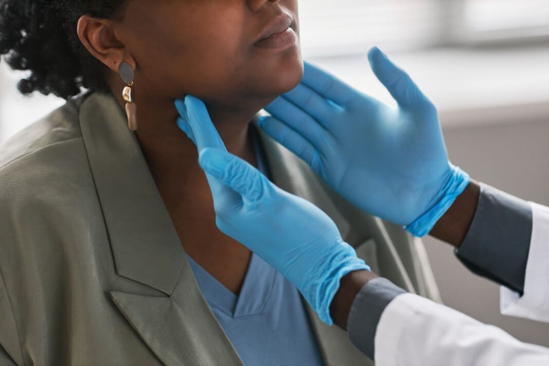Close up male doctor palpating neck examining woman in clinic